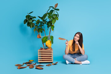 Photo of thoughtful minded girl dressed yellow t-shirt holding yellow leaf looking withered flower...