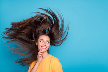 Photo of funky cunning girl dressed yellow t-shirt finger chin hair flying looking back empty space isolated blue color background