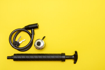 bicycle lock with keys, bell and pump on yellow background with copy space