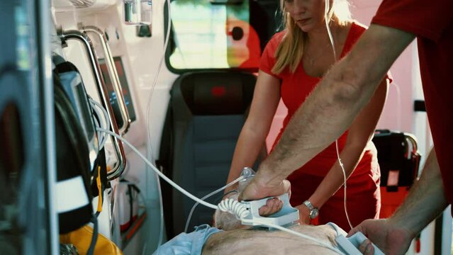 Paramedics team using a defibrillator and ventilation mask to bring the man back to life in an ambulance