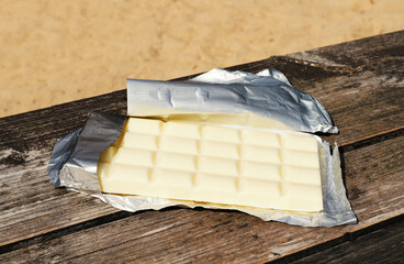 White chocolate in foil on a wooden surface.