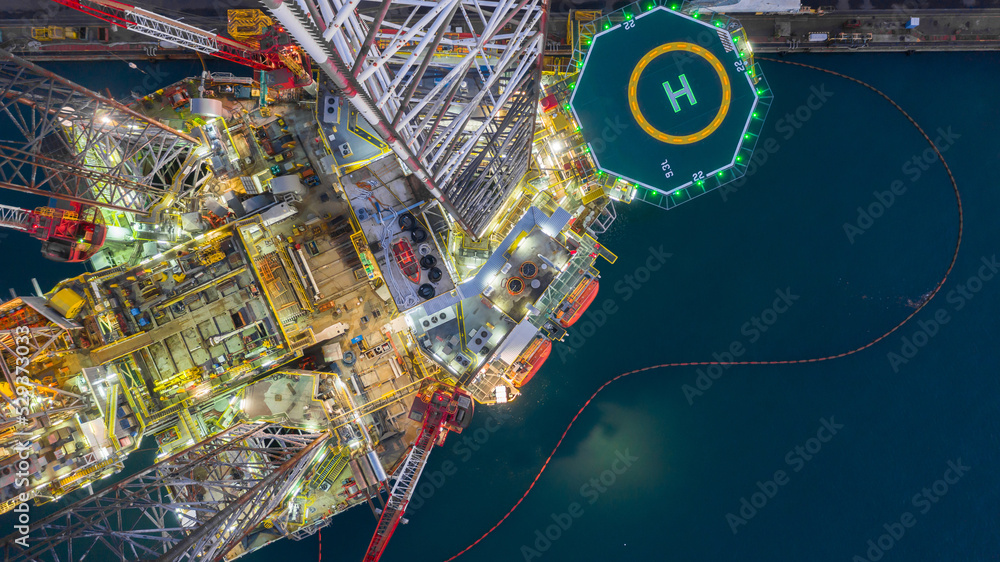 Wall mural Aerial view jack up rig under maintenance at night, Aerial view of jack up rig with towing vessel during towing operation, Offshore vessel in floating dock and jack up rig under repairs. - Wall murals