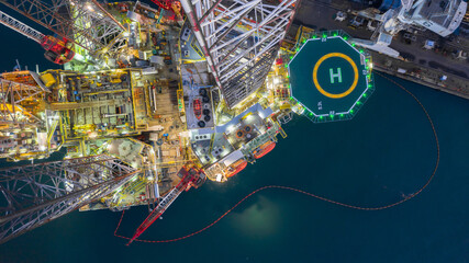 Aerial view jack up rig under maintenance at night, Aerial view of jack up rig with towing vessel during towing operation, Offshore vessel in floating dock and jack up rig under repairs.