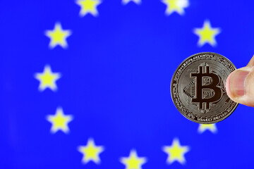 A Bitcoin currency and the background of the flag of the European Union, selective focus.