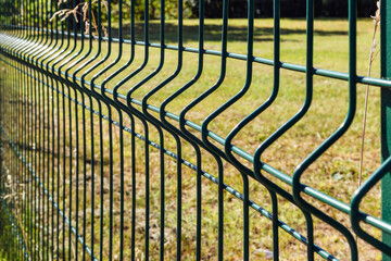 Segmented green wire fence in field close up