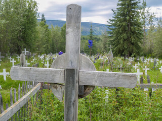 Old wooden. cross close up with defocused field of white crosses of graveyard.