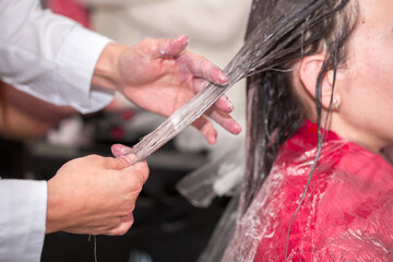 Hairdresser stylist takes care of girl's hair. Hair care procedures in a beauty salon. Hair treatment, coloring and styling. Botox and hair lamination keratin straightening.