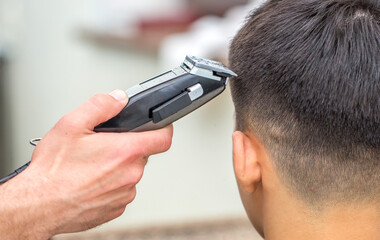 Male hairdresser, grooming men. Haircut styler and trimmer. The master cuts a man, shaves his temples and neck. The client at the hairdresser looks in the mirror. barbershop