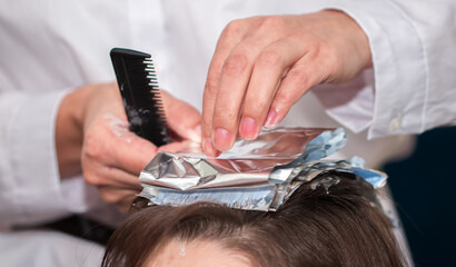 Hairdresser stylist takes care of girl's hair. Hair care procedures in a beauty salon. Hair treatment, coloring and styling. Botox and hair lamination keratin straightening.