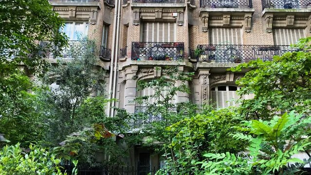 BUILDING PARIS surrounded by green plantings with beautiful architectural design. View of traditional style houses in Paris, France. It's like you are in a fairy tale. Corner view. Camera moves up.