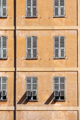 Typical facade in the south of France, on the French Riviera, windows with colored shutters.