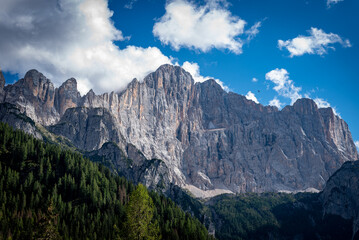 clouds over the mountains dolomiti, with blue sky and green trees in italy