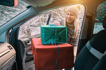 Woman Giving Gifts. Female is holding presents and delivering them on her car to Home. Holidays...