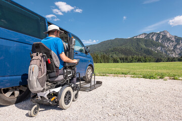 Man with disability using hydraulic wheelchair lift to get in the van, after a summer day spent on...