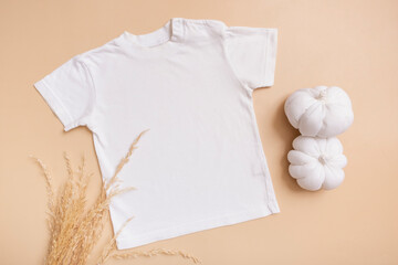 White baby t-shirt top view. Mock-up for logo, text or design on beige background. Flat lay child...