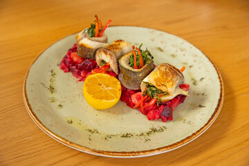 Baked fish in a roll with vegetables on a white plate