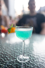 Glass of Blue Lagoon cocktail on light grey table, outdoors