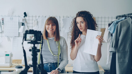 Young attractive vloggers clothing designers are recording video for their vlog. Women are showing...