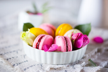 Good morning. Delicious macarons desserts are served on the table in the morning for breakfast. Beautiful light still life with a rose highlight. Baking for breakfast on a light table with copy space