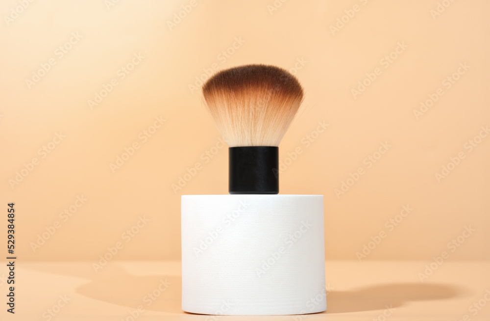 Wall mural cosmetic brush for powdred or blush application on white geometric podium. cosmetic accessories, mak