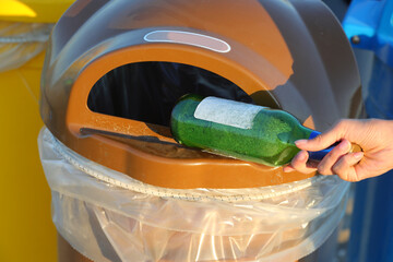 glass bottle thrown into the correct recycling bin to recover the used material