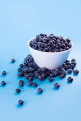 Fototapeta na wymiar Beautiful fresh blueberries in a white bowl on a blue background.Vegan and vegetarian concept. Summer healthy food.