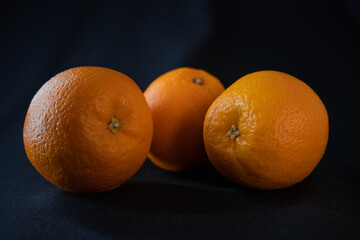 three oranges on a dark background