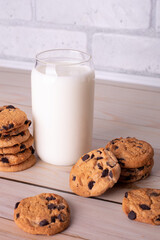 Flatlay an after school snack of chocolate chip cookies and an glass cup of milk. The cookies with chocolate drops and on a rustic wood kitchen table, with copy space. yummy and tasty
