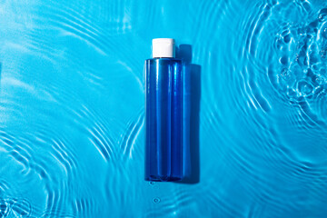 Mock up blue miccelar water, moisturizing in water on blue background. Template for design.