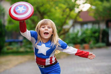 Funny little power super hero child in superhero costume. Happy preschool girl having fun with...