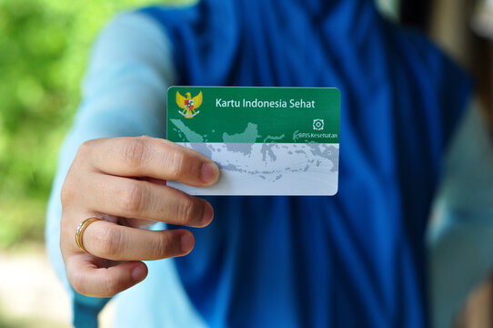 A young mother holds a Healthy Indonesia Card (Health Insurance card from the Government of Indonesia)
