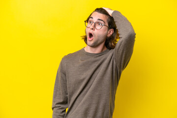Obraz premium Caucasian handsome man isolated on yellow background doing surprise gesture while looking to the side
