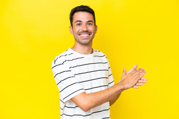 Young handsome man over isolated yellow background applauding