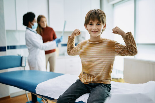 Happy kid flexing his muscles after medical examination at doctor's office.