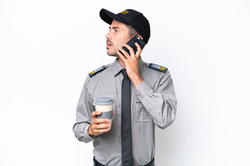 Young safeguard man over isolated white background holding coffee to take away and a mobile