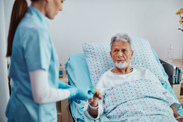 Senior patient getting pulse oximeter on his finger during his recovery in hospital.