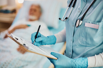 Close up of nurse writing data into medical record of hospitalized patient. - obrazy, fototapety, plakaty
