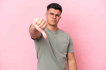 Young caucasian handsome man isolated on pink background showing thumb down with negative expression