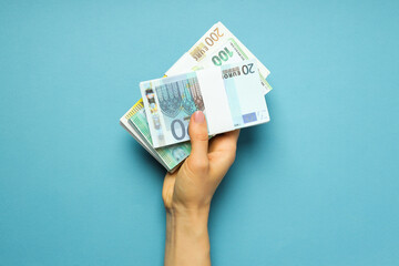 Concept of financials, female hand holds money on blue background