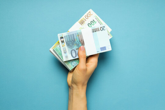 Concept Of Financials, Female Hand Holds Money On Blue Background