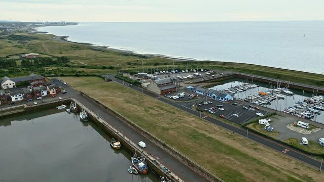 Aerial footage of the small English fishing village of Maryport in Allerdale a borough of Cumbria, England.
Shot using a drone and looking down onto the harbour, boats, and surrounding town.