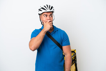Young caucasian man with thermal backpack isolated on white background having doubts and with confuse face expression