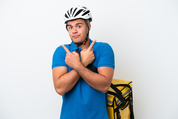 Young caucasian man with thermal backpack isolated on white background pointing to the laterals having doubts