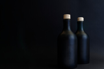 Black gin bottles, dark shot of two gin bottles with natural cork. The bottles are arranged on the...