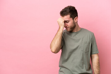 Young caucasian man isolated on pink background with headache