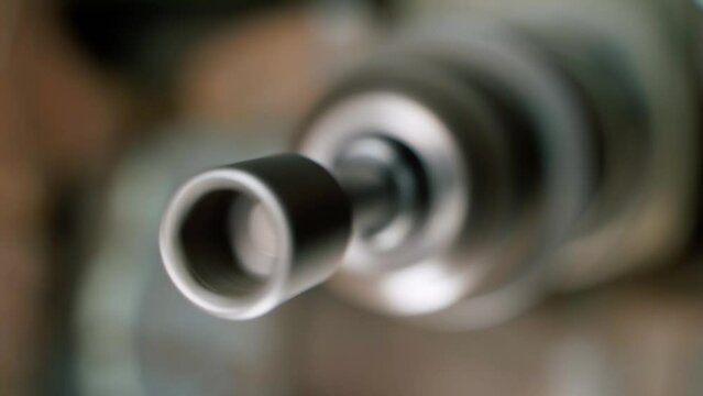 A close-up hexagon socket on a screwdriver is spinning in a drill chuck against a blurred background. Nozzle for loosening nuts on a wrench