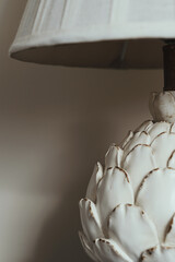 Close up image of artichoke lamp set against a plain background. Neutral colour palette. Portrait orientation image with copy space.