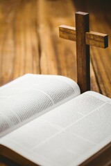 Bible and wooden cross on hardwood floor