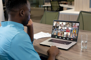 African american businessman in office making laptop video call with twelve diverse colleagues