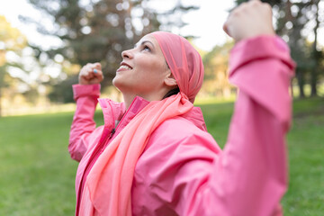 Medical and health concept. Healthy woman showing her power fist against female cancer She is wearing a pink scarf and a pink sweater. fight against cancer.